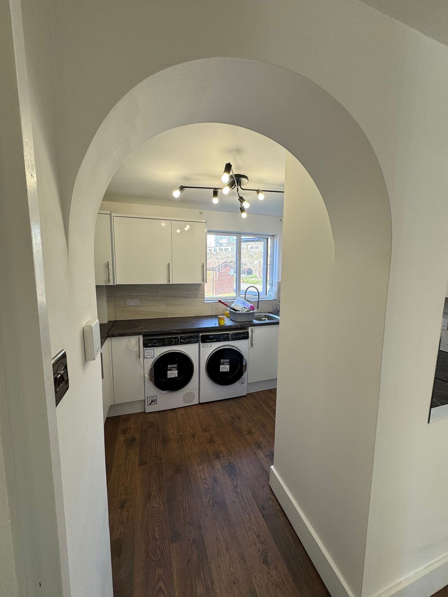 Full Property Refurbishment in Hammersmith: The kitchen through the arched doorway, new flooring running through