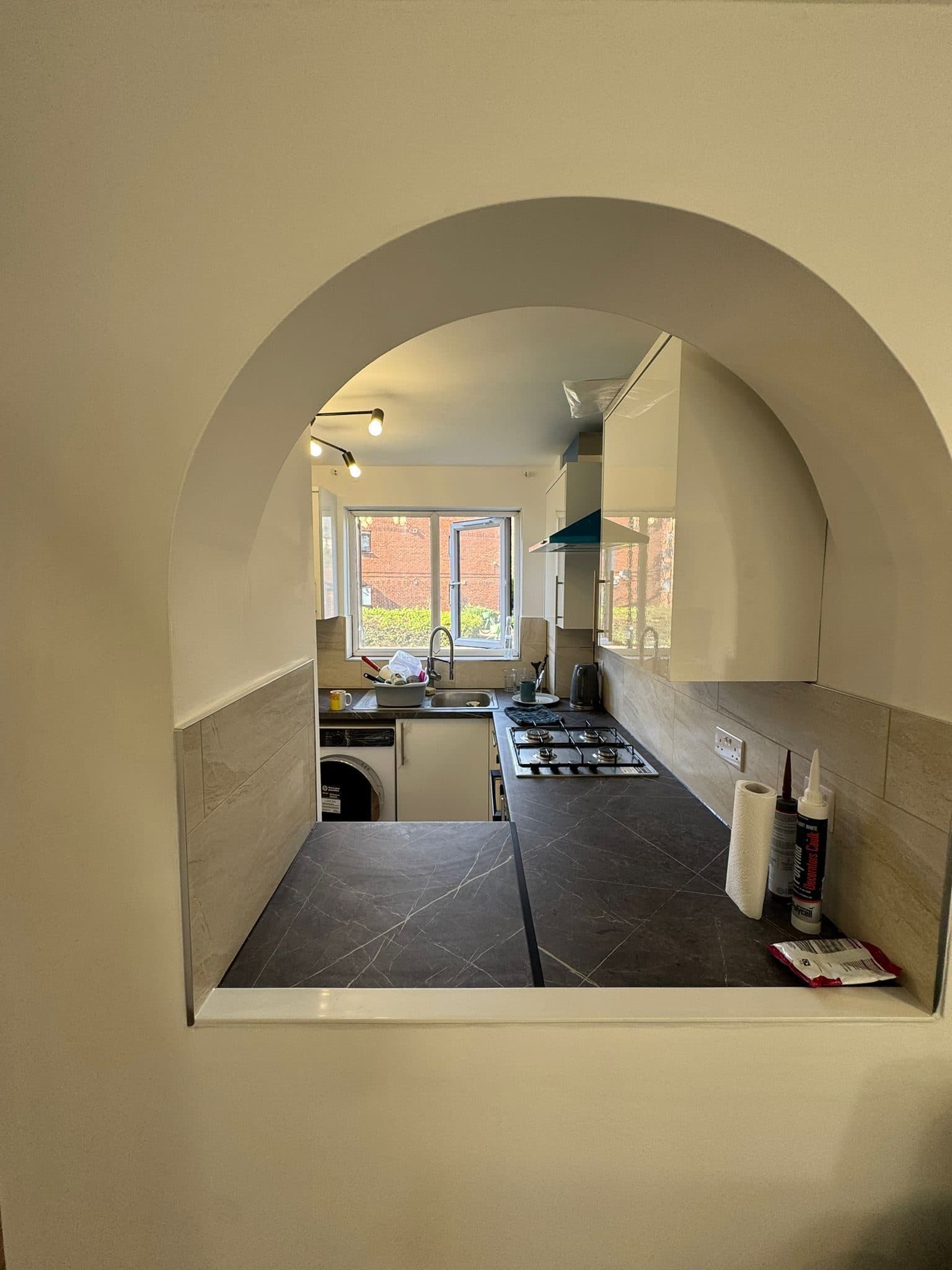 Full Property Refurbishment in Hammersmith: The kitchen seen through the arched hatch