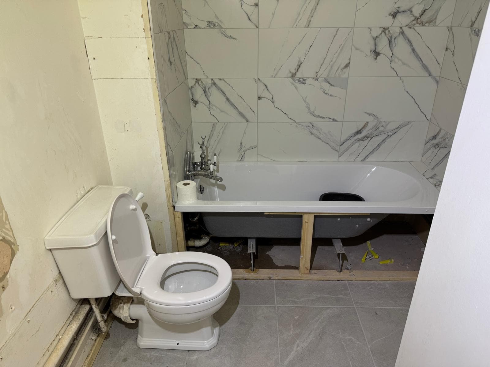 Marble Family Bathroom in Hammersmith: Bath back in, walls tiled and the floor down