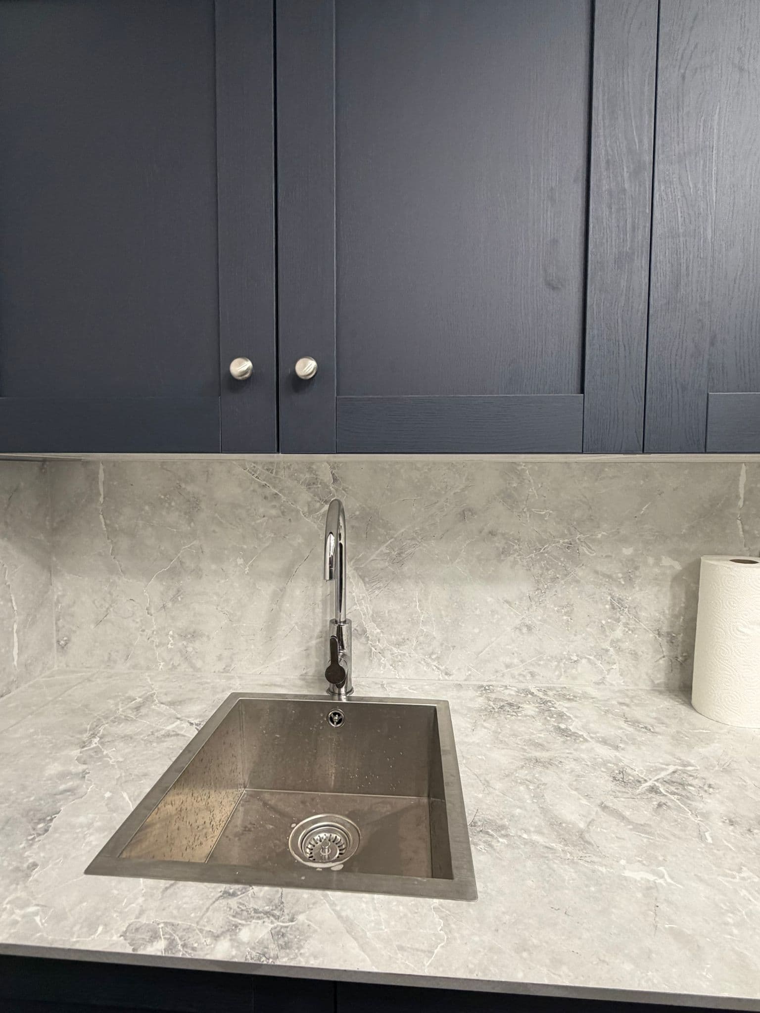 Navy Shaker Kitchen in Mayfair: The sink and tap against the marble-effect splashback