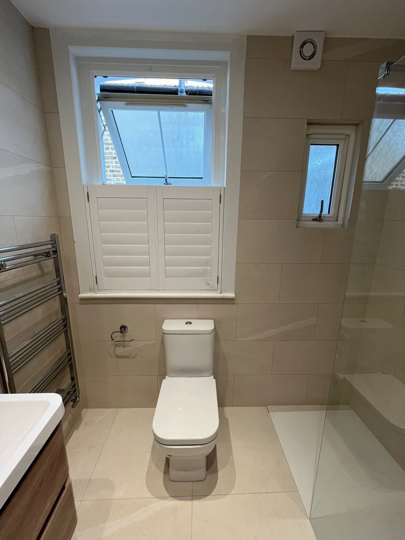 Bathroom Layout Transformation in Tooting: The toilet beneath the shuttered window, with a heated towel rail