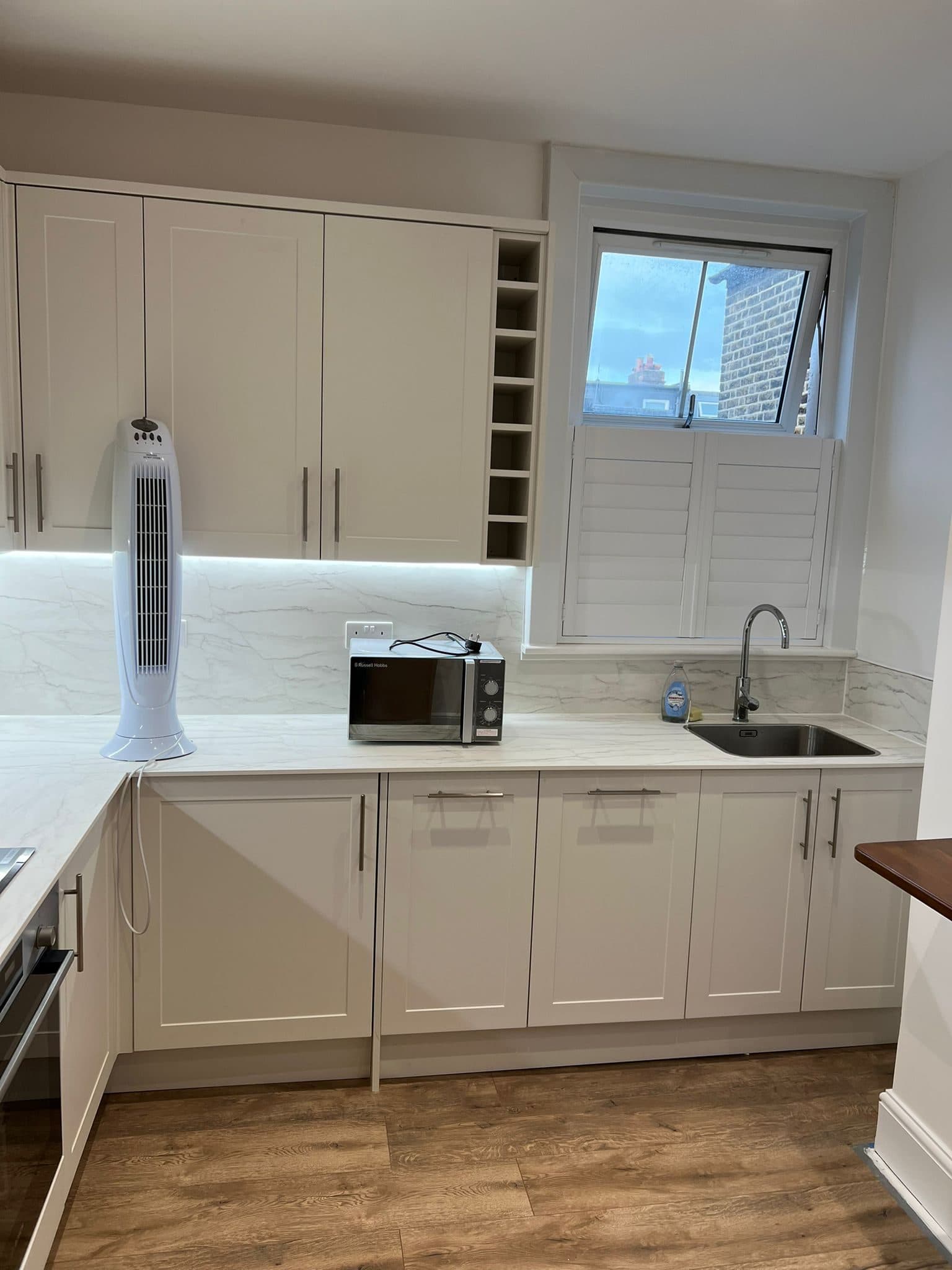 Kitchen Renovation in Tooting: The sink run below the window, lit from under the wall units