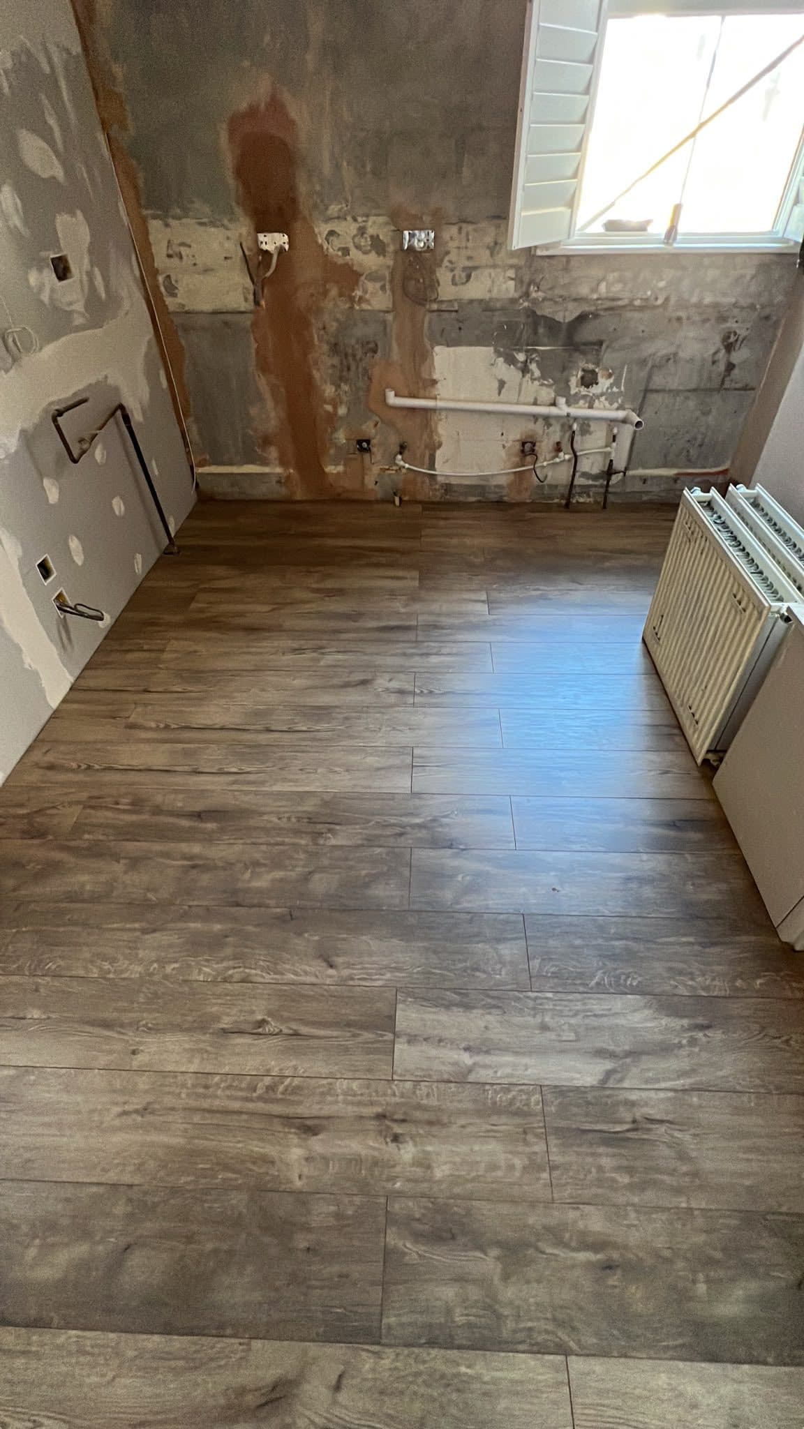 Kitchen Renovation in Tooting: The new floor down, with pipework in place under the window